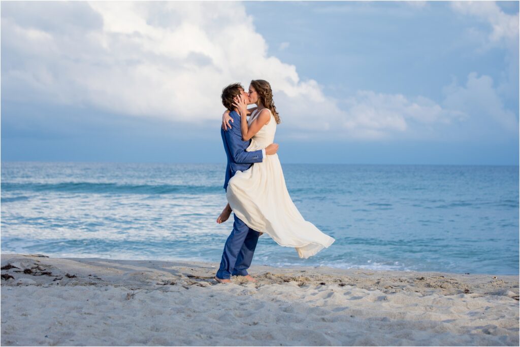 Bride in grooms arms on beach